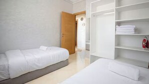 A hotel room with two beds, a wardrobe, and a bathroom visible through an open door. - Peaceful place near stadium and airport (Tanger)