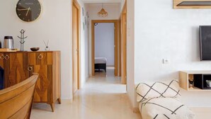 A modern interior with a wooden cabinet, a clock, a sofa, and a television. - Peaceful place near stadium and airport (Tanger)