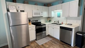Una cucina moderna con mobili bianchi, elettrodomestici in acciaio inossidabile e pavimento in legno.