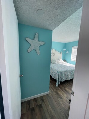 A room with teal walls, a starfish decoration, a bed with a patterned bedspread, and a wooden floor. - Young's Plantation Paradise-steps away from beach (Gulf Shores)