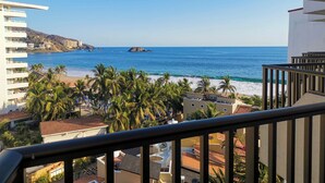 A coastal view from a balcony with a clear sky, palm trees, and buildings in the background. - Condominios Torre Continental Ixtapa (Ixtapa)