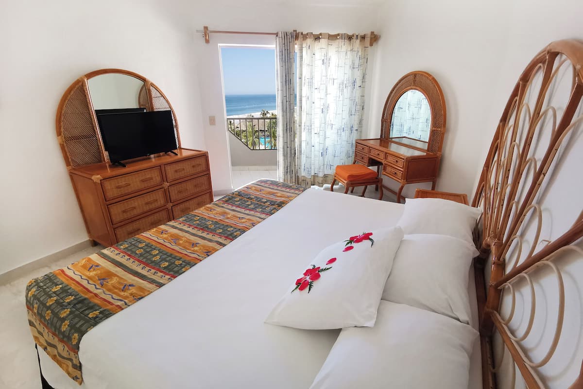 Un dormitorio con cama, cómoda, escritorio y televisor.