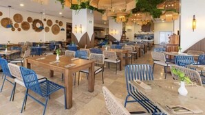 A restaurant with wooden tables and blue chairs, hanging lights, and green foliage on the ceiling. - Condominios Torre Continental Ixtapa (Ixtapa)