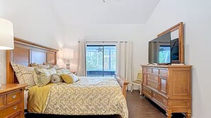Une chambre à coucher comprenant un lit, une commode, un miroir et un ventilateur de plafond.
