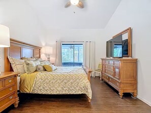 A bedroom with a bed, dresser, mirror, and a ceiling fan. - Lake Side Spa Home (Naples)