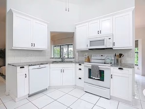 Eine moderne Küche mit weißen Schränken, einer Mikrowelle, einem Backofen und einem Geschirrspüler.