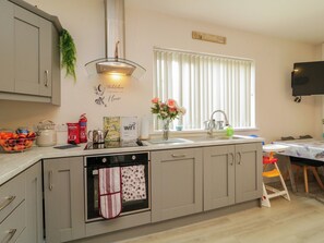 Una cocina moderna con horno empotrado, un lavamanos y una ventana con persianas.