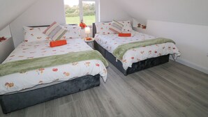 Quarto com duas camas, uma janela com vista e uma mesinha com abajur.