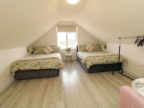 Un dormitorio con dos camas, una mesita con flores y un ventanal.