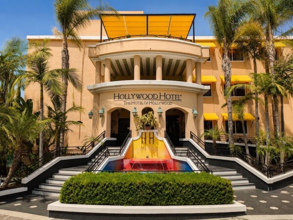 The Hollywood Hotel entrance with a central fountain, palm trees, and a yellow awning. - 2 Connecting Suites at a  Hotel (Los Angeles)