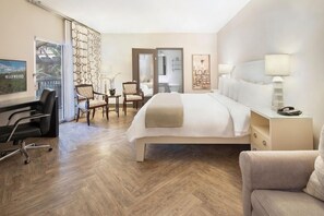 A hotel room with a large bed, a desk, two chairs, a nightstand, and a view of the outdoors. - 2 Connecting Suites at a  Hotel (Los Angeles)