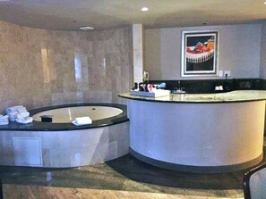 A modern bathroom with a curved bathtub, a sink, and a towel rack. - 2 Connecting Suites at a  Hotel (Los Angeles)