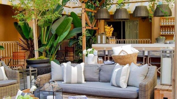 An outdoor seating area with wicker furniture, a wooden table, and a large planter.