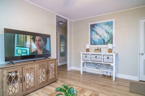 Ein Wohnzimmer mit Fernseher auf einer Holzkommode, einer weißen Unterhaltungseinrichtung und einem Gemälde an der Wand.