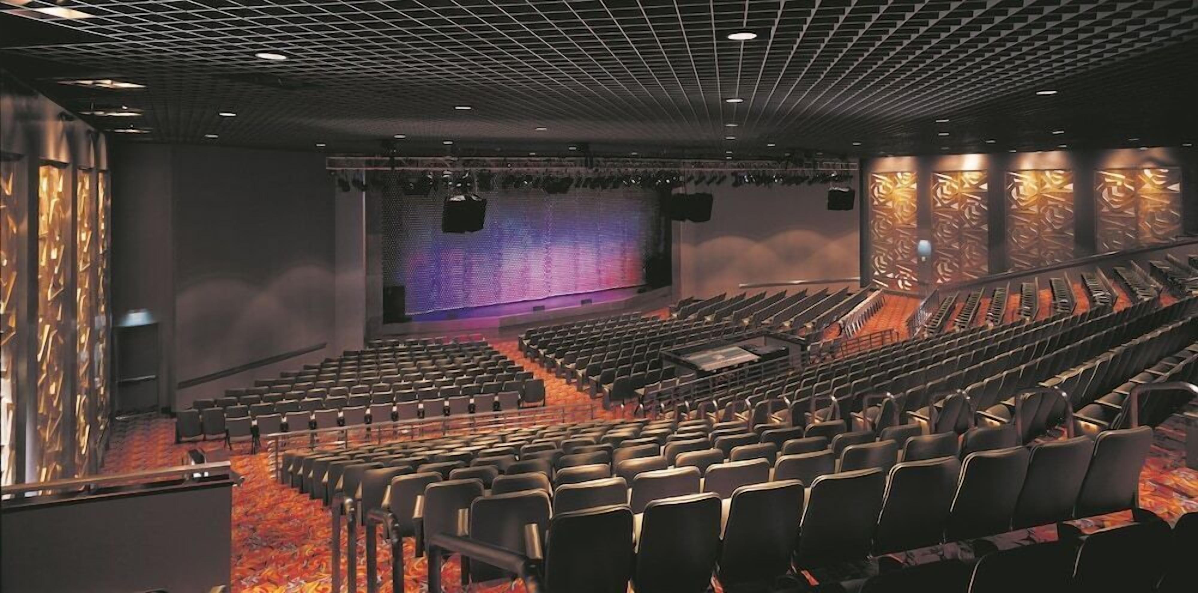 A theater with rows of seats, a stage, and a patterned wall.