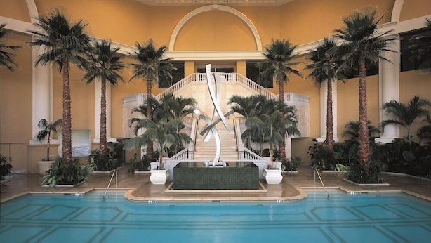 A pool area with palm trees, a central staircase, and a tiled floor.