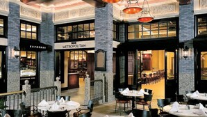 A restaurant with a sign reading 'METROPOLITAN' and a visible 'ESPRESSO' sign. Tables are set with napkins and cutlery.