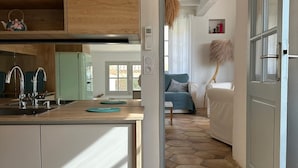 Ett modernt kök med träskåp, en inbyggd köksö och utsikt över ett vardagsrum med en soffa och en lampa.