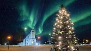 A snow-covered landscape with a lit Christmas tree and a church. - Apartment Medio in Bardu (Bardu)