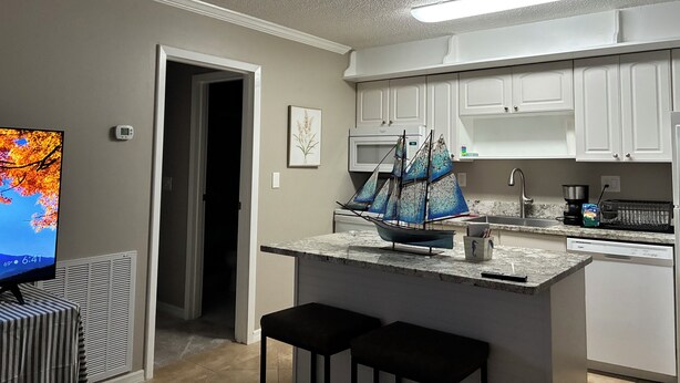 A kitchen with white cabinets, a microwave, a coffee maker, and a small ship model on the counter. - Hidden Gem Sarasota Getaway Near Siesta Key (Sarasota)