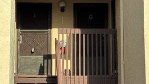 A building entrance with a metal gate, two windows with letters, and a wall-mounted light fixture. - Hidden Gem Sarasota Getaway Near Siesta Key (Sarasota)
