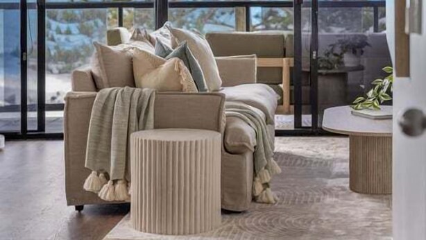 A modern living room with a large window, a sofa, a coffee table, and a side table. - Summer Cove - Beachfront with Pool (Sunshine Coast)