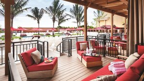 A covered outdoor seating area with red sofas and a pool in the background. - 1-Bedroom Suite at a 4.5⭐️ Hotel (Atlantic City)