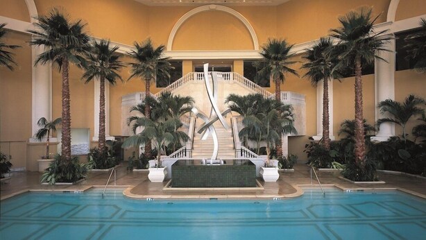 A pool area with palm trees, a central staircase, and a tiled floor. - 1-Bedroom Suite at a 4.5⭐️ Hotel (Atlantic City)