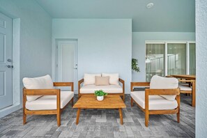 Eine Terrasse mit einer Couch-Garnitur aus Holz, einem Couchtisch und einer Tür.