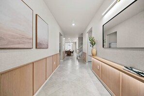 A hallway with wooden paneling, a large mirror, and a dining area in the distance. - 10BR house sleeps 24 with pool and game room (Clermont)