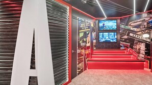 A modern interior with a red carpeted staircase, a large white letter 'A' on the wall, and various posters and signs. - 10BR house at Windsor Cay Resort (Clermont)