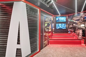 Ein modernes Interieur mit einer roten Teppichstufenleiter, einem großen weißen Buchstaben 'A' an der Wand sowie verschiedenen Postern und Schildern.