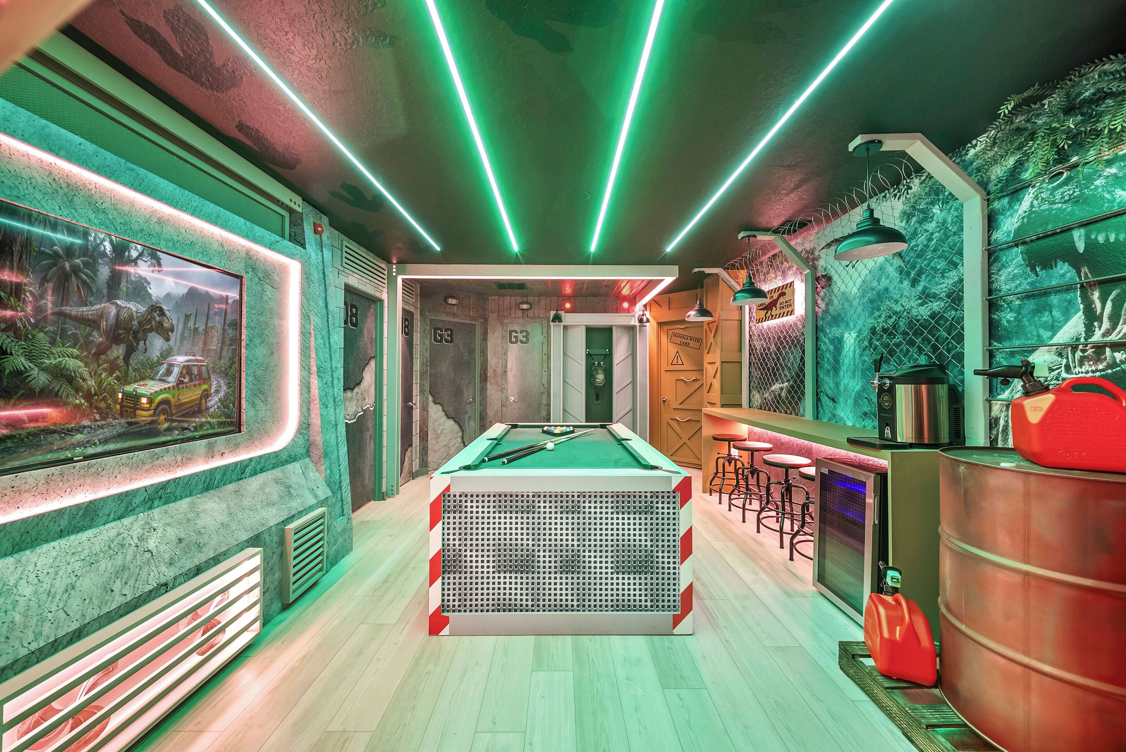 A pool table with a green felt surface, surrounded by a bar area with stools and a neon-lit ceiling.