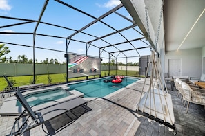 A covered outdoor swimming pool with lounge chairs and a view of a race track. - 10BR house sleeps 27 with private pool (Clermont)