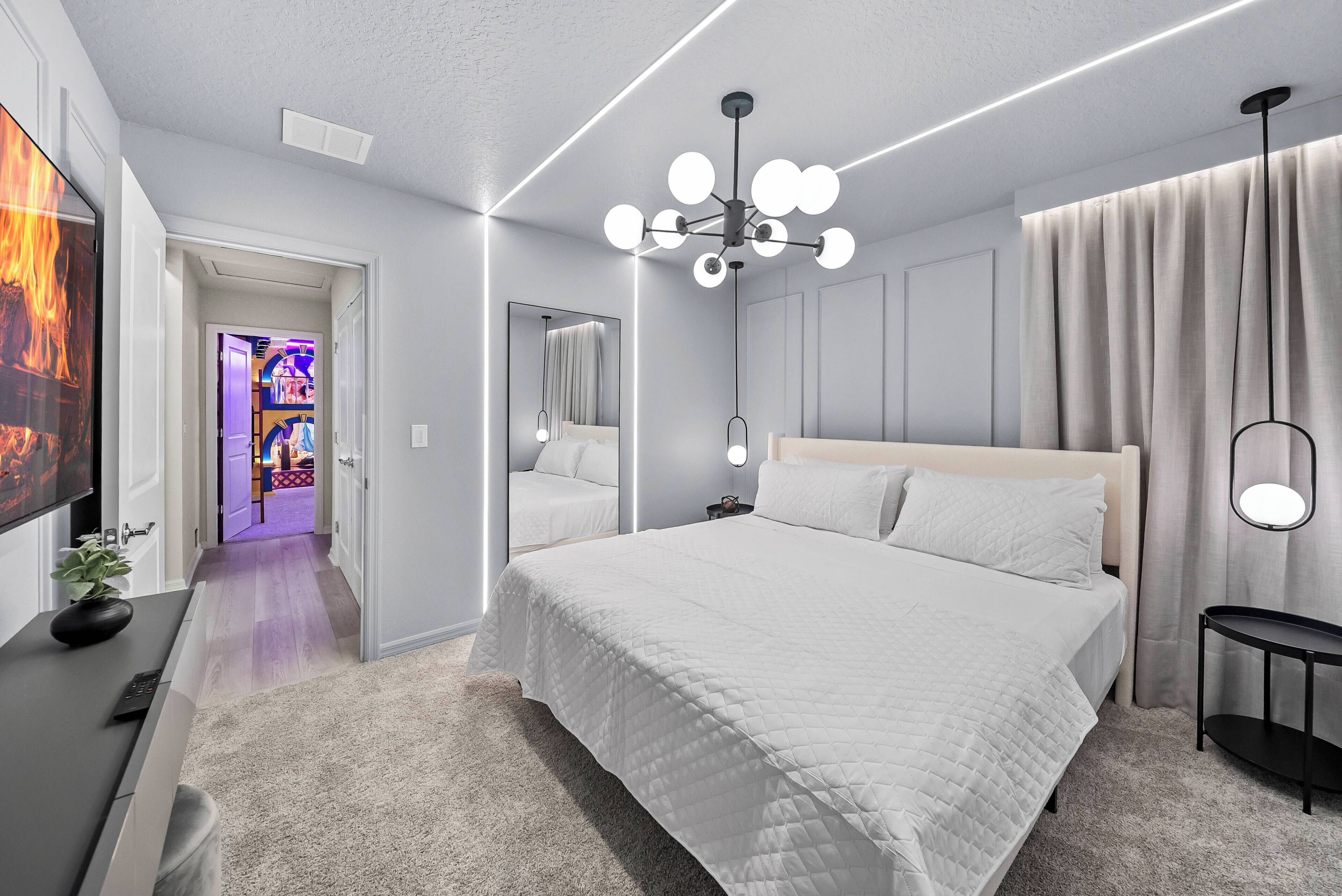 A modern bedroom with a large bed, a ceiling light fixture, and a mirror.