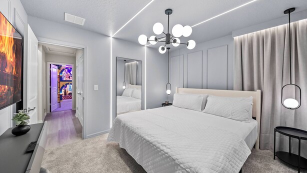 A modern bedroom with a large bed, a ceiling light fixture, and a mirror. - 10BR house at Windsor Cay Resort (Clermont)