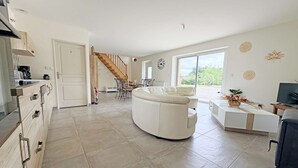 Ein großzügiger Wohnbereich mit Sofa, Esstisch und einer Treppe zu einer weiteren Ebene.