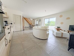 Un vaste espace de vie comprenant un canapé, une table à manger et un escalier menant à un autre niveau.