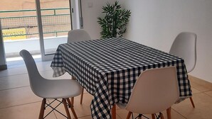 A dining area with a checkered table and four chairs, a potted plant, and a view through a glass door. - Apartment in Portimão City Centre (Portimão)