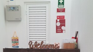 A reception desk with a 'Welcome' sign, a first aid sign, and a fire alarm sign on the wall. - Apartment in Portimão City Centre (Portimão)