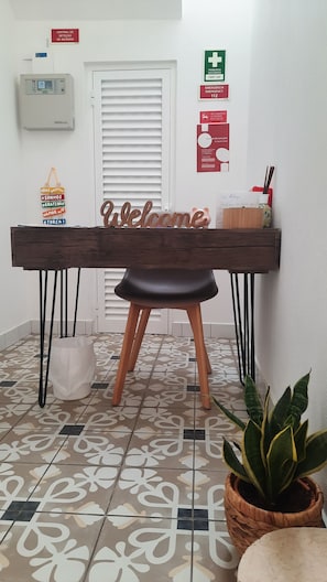 A reception desk with a 'Welcome' sign, a first aid sign, and a fire alarm sign on the wall. - Apartment in Portimão City Centre (Portimão)