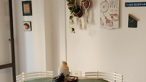 A dining area with a round wooden table, white chairs, green placemats, and a hanging plant. - Like at Home, Apartment in the center of Cordoba Capital, close to everything! (Córdoba)
