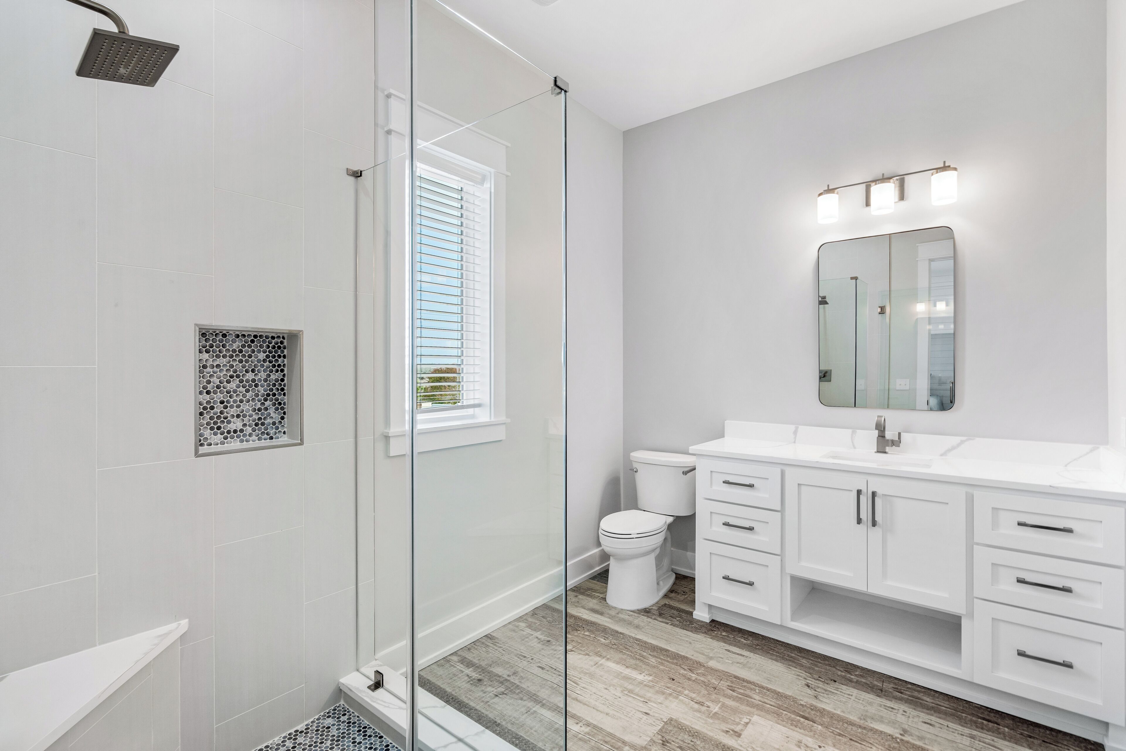 A modern bathroom with a glass shower enclosure, a toilet, and white cabinetry.