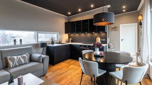 Una cucina moderna con pensili neri, un tavolo da pranzo rotondo e un divano grigio.