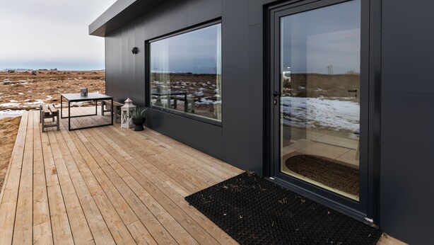 Un edificio moderno con ampie finestre, un patio in legno e vista su un paesaggio arido.