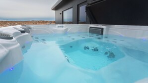Una vasca idromassaggio con pannello di controllo, circondata da un edificio moderno con ampie finestre.