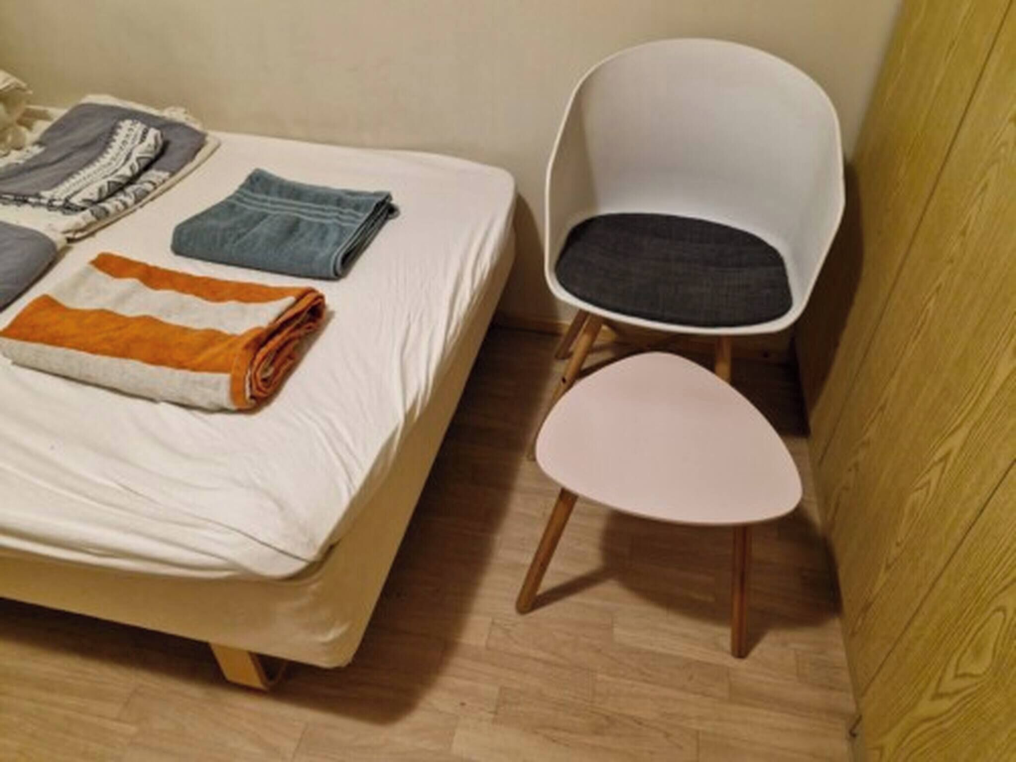 Une petite pièce avec un lit, une chaise et un plancher en bois.