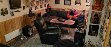 Una sala de estar con un sofá, una mesa de centro, una estantería y un televisor.