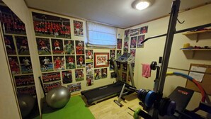 A home gym with exercise equipment, a green mat, and sports memorabilia on the walls.
