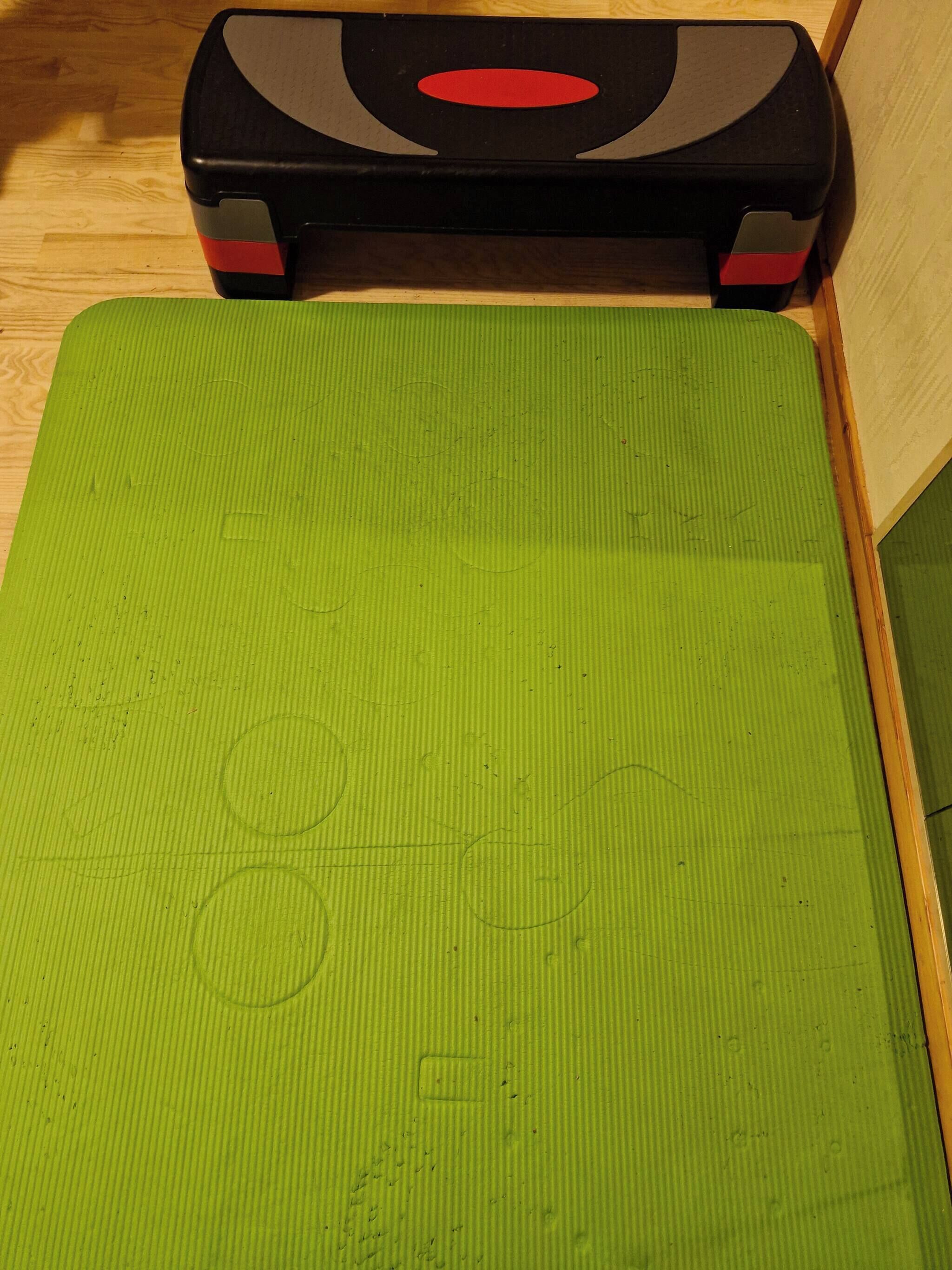 A green exercise mat with a black and red object on top.